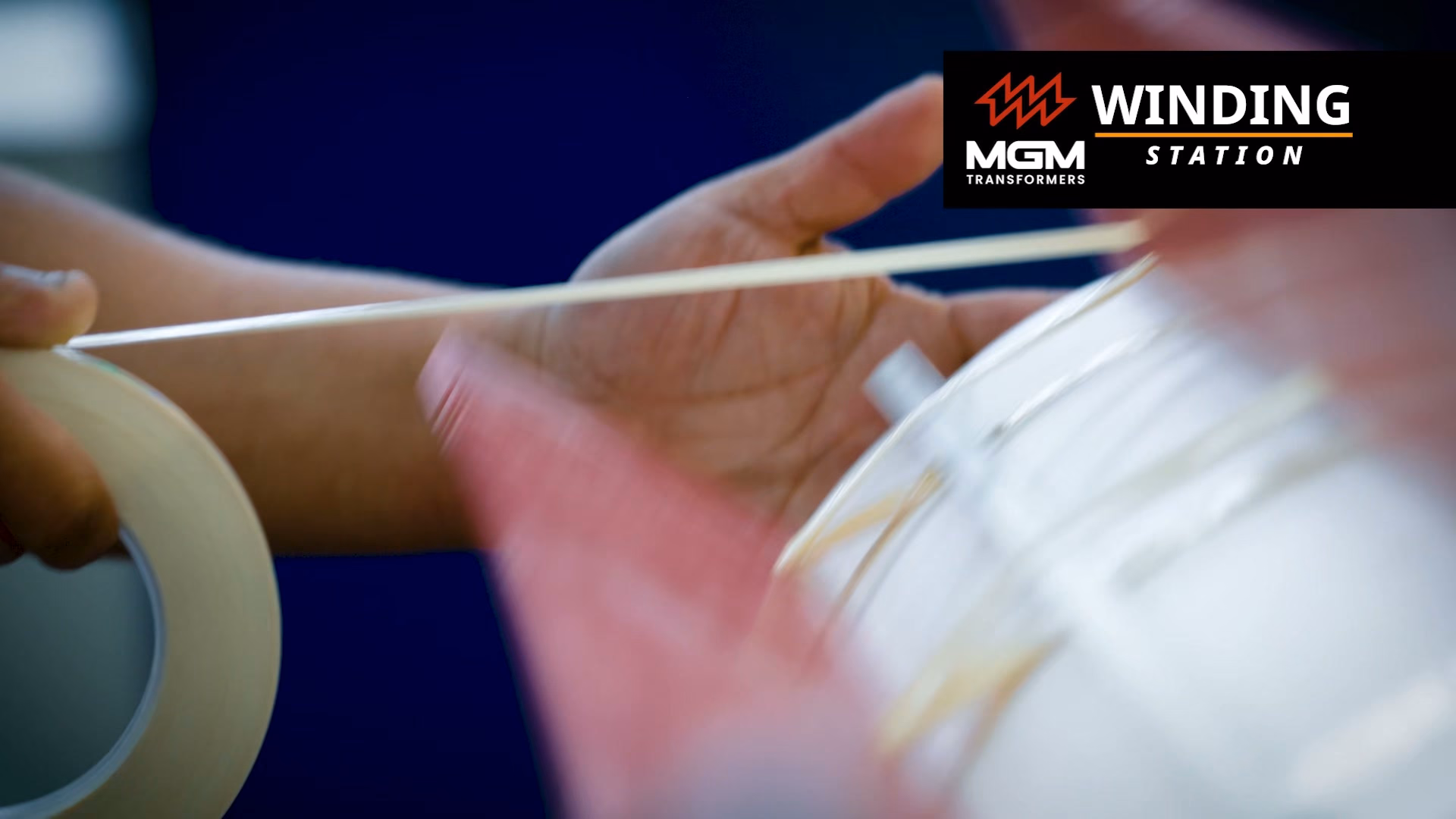 A worker's hands rolling insulation tape onto a winding, in close-up